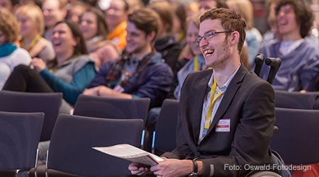 Lachender junger Mann inmitten des Publikums auf der weltwärts-Konferenz. Foto: Oswald-Fotodesign.